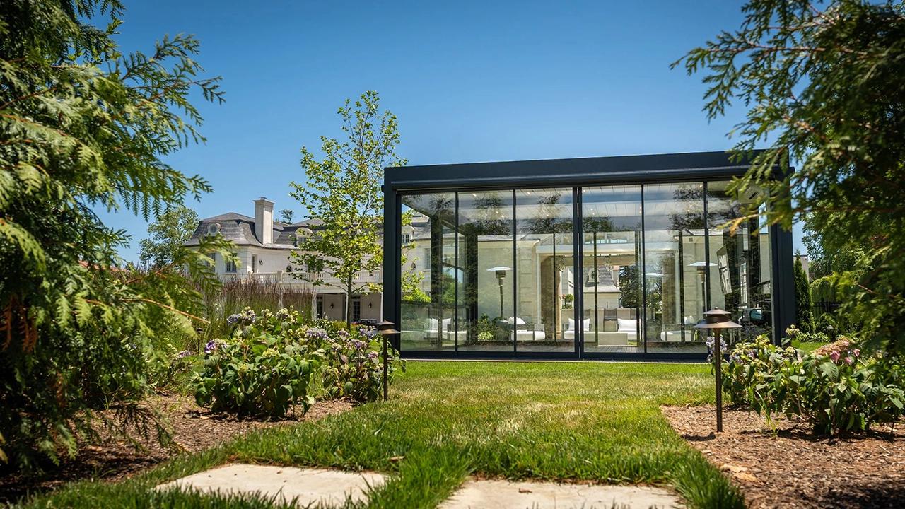 Luxury freestanding glass and steel pergola garden room in a lush green compound — high-end outdoor living in Kenya