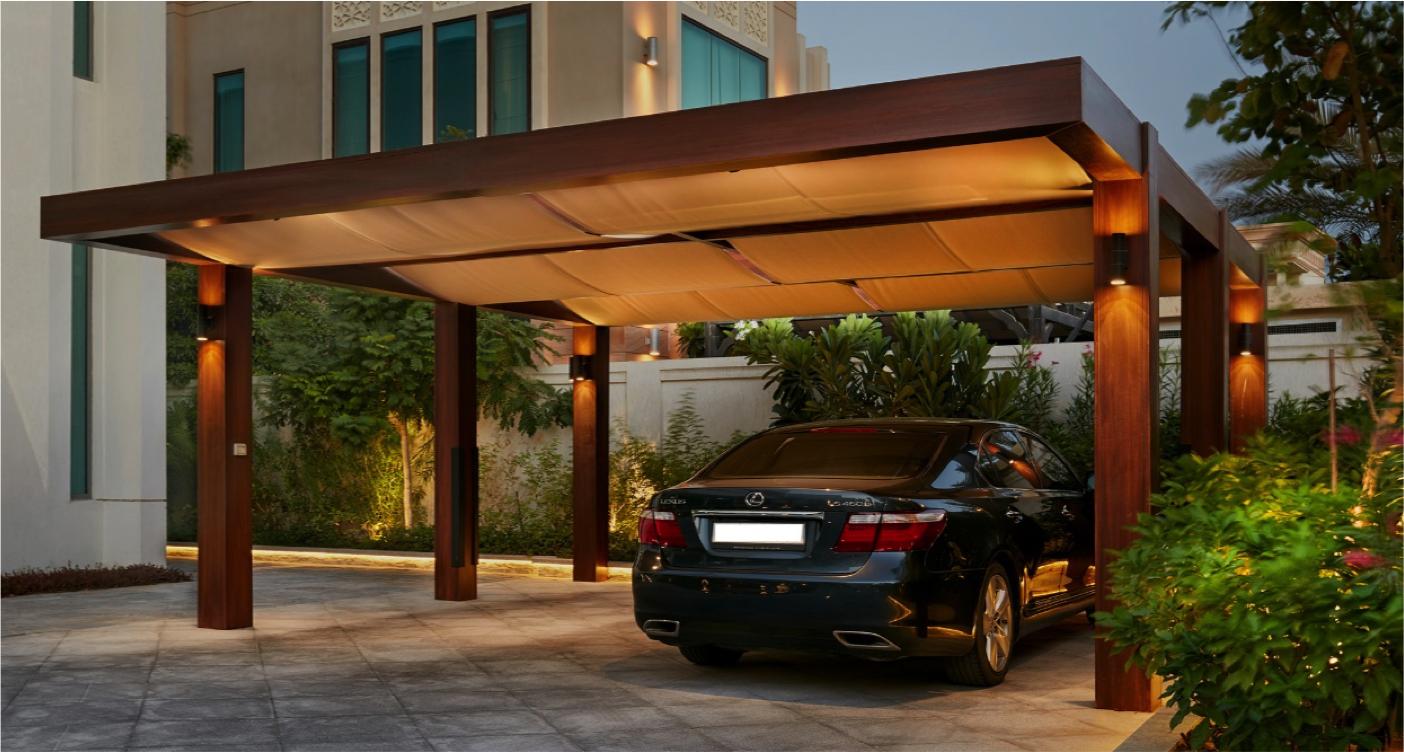 Premium hardwood carport pergola with wall lighting and fabric canopy over a luxury car driveway — modern car shade pergola design Kenya