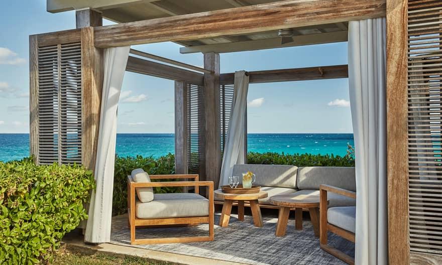 Resort-style timber pergola with white curtains and outdoor lounge furniture overlooking the ocean — coastal Kenya Diani Kilifi design