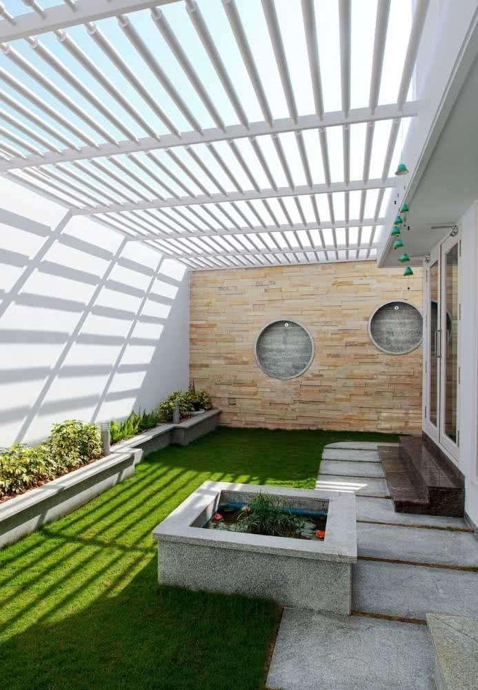 White slatted pergola over a courtyard garden with a koi pond water feature and green lawn in a Kenya outdoor living design