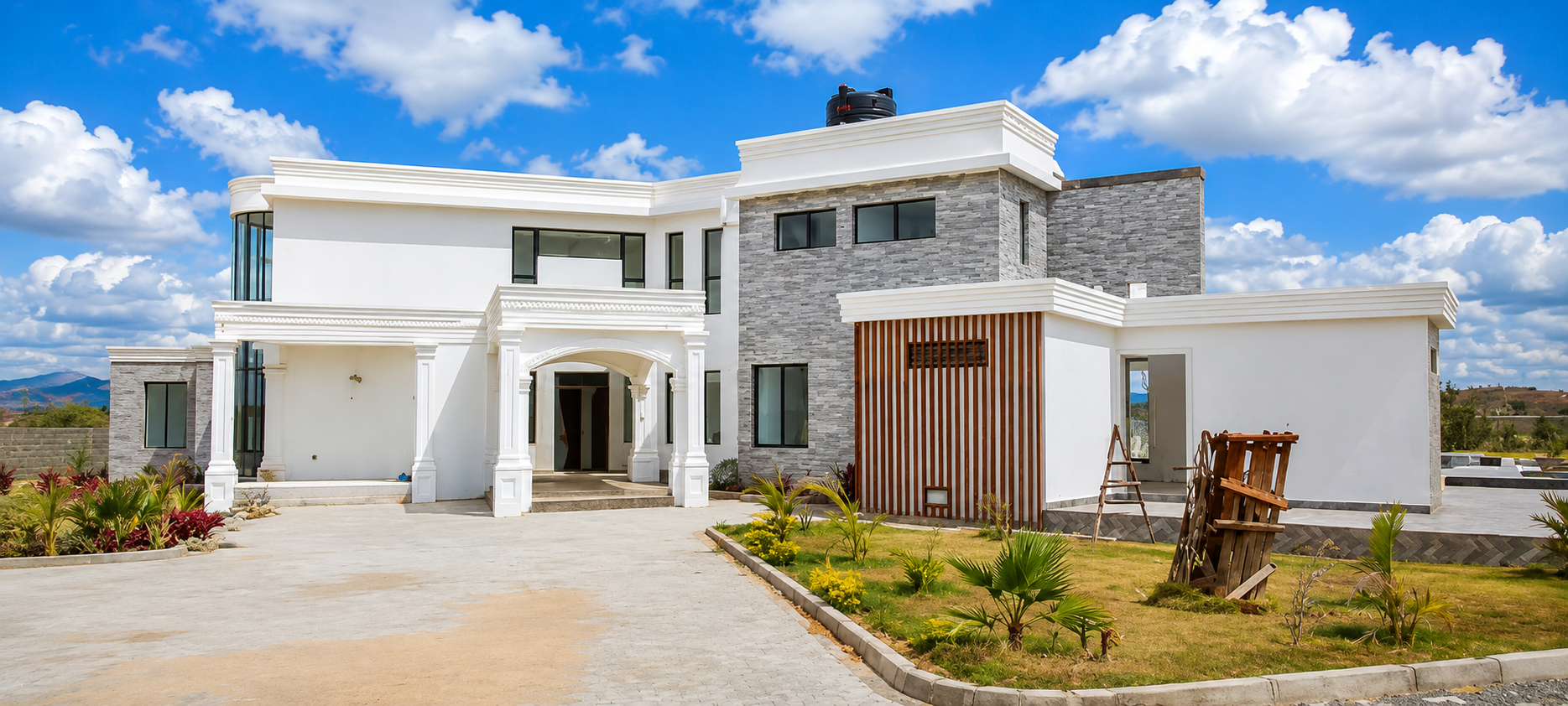Konza Mansion — completed front facade in daylight, showing grey stacked stone, white cornice moulding and timber slat door