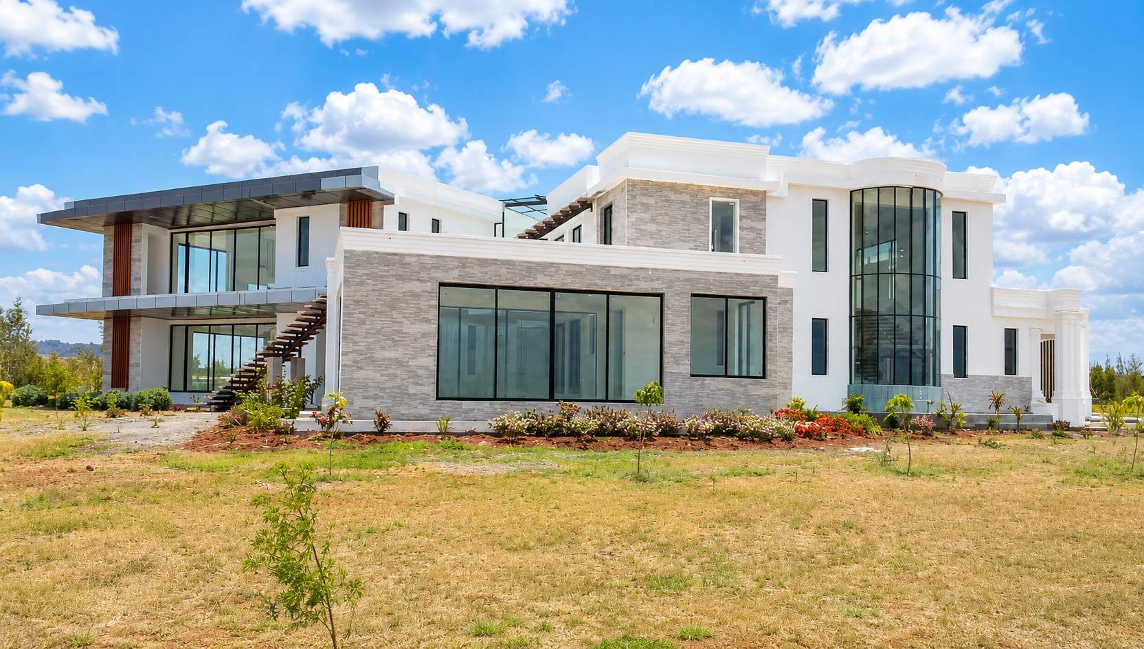 Completed side elevation of Konza Mansion showing the grey stacked stone base, white stucco upper level and rooftop garden balustrade