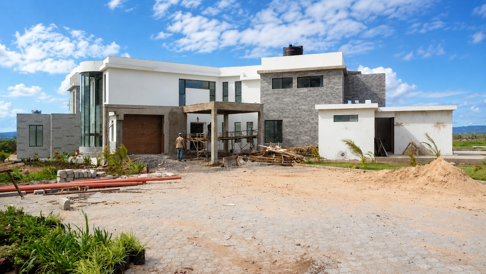 Konza Mansion under construction, showing the curved glass stair tower and grey stone cladding being installed